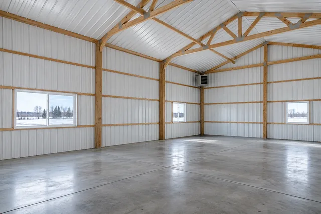 Bright insulated pole barn interior with white steel liner panels, sealed slab and a unit heater in the corner