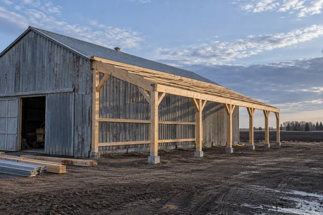 New lean-to addition being framed off the sidewall of an existing weathered pole barn